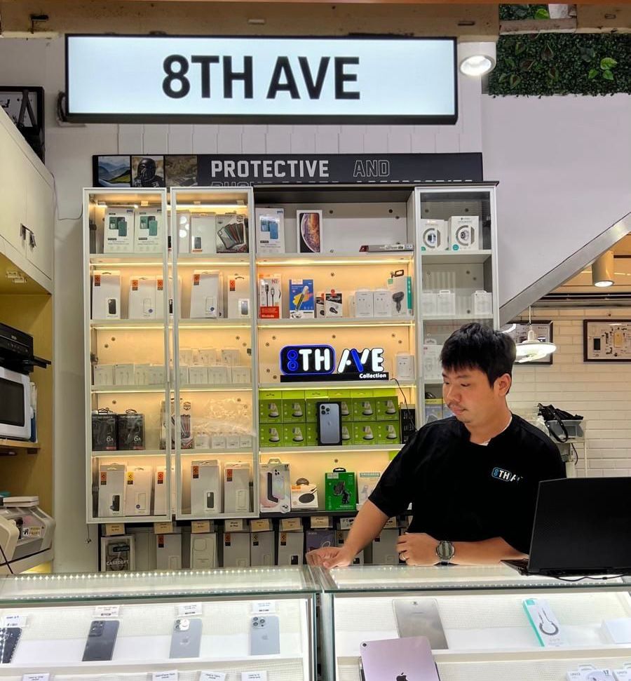 Person working at a store counter with '8th Ave' branding in the background